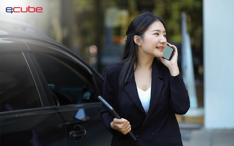 Businesswoman on phone beside ECube rental car.