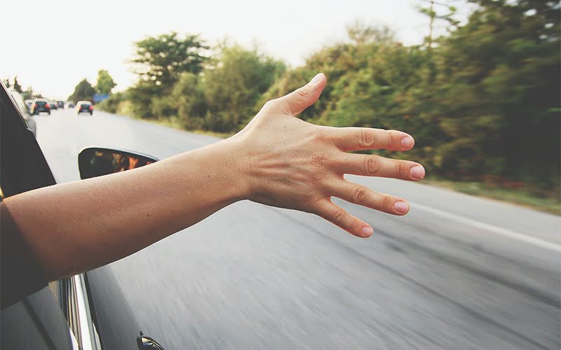 arm outside a window of a car running in high speed