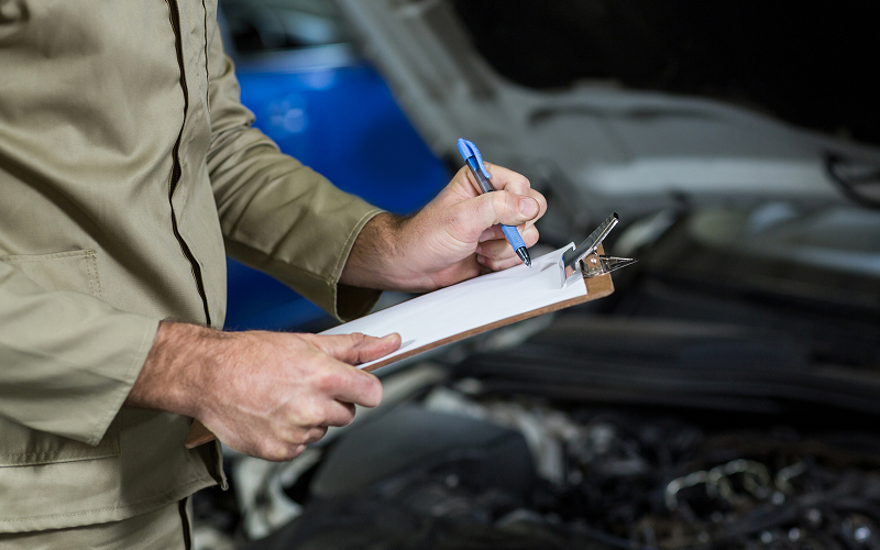Mechanic filling out inspection checklist for a rental vehicle